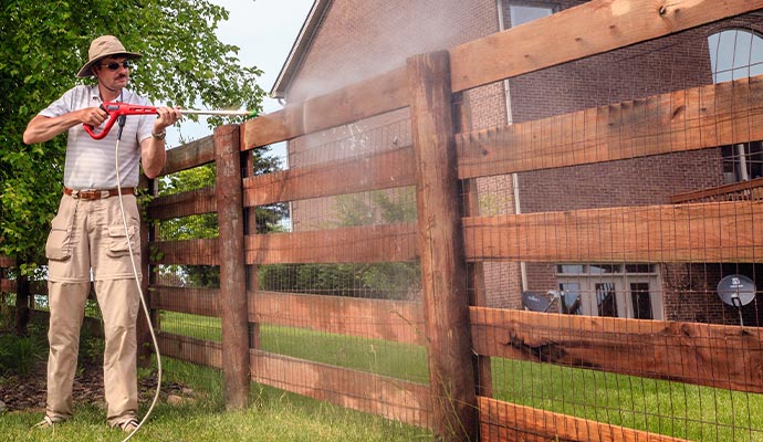 man wearing hat fence power washing