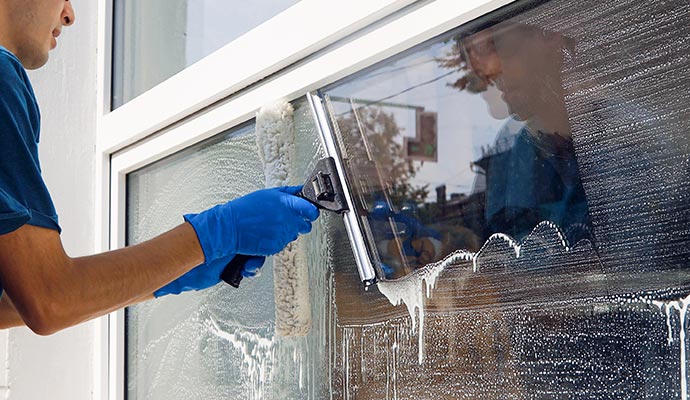 professional cleaning service in overalls washes the glass of the windows of the facade of the building