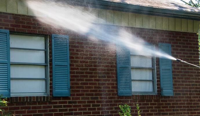 spray of water on siding and brick work on the side of a building