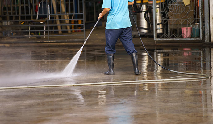 Worker using power pressure tools to clean the floor