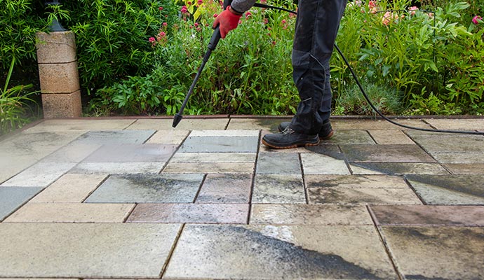 worker cleaning stone slabs on patio with the high pressure cleaner