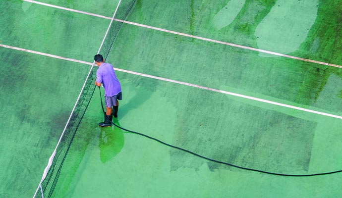 worker cleaning tennis court